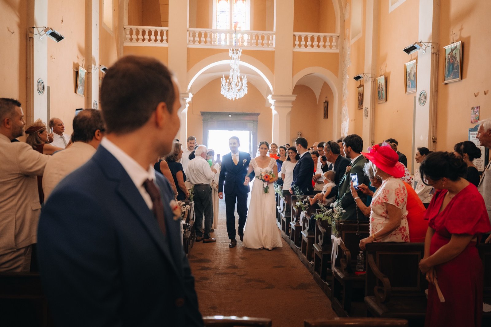 Pauline remonte l'allée de l'église, Hadrien de dos au premier plan