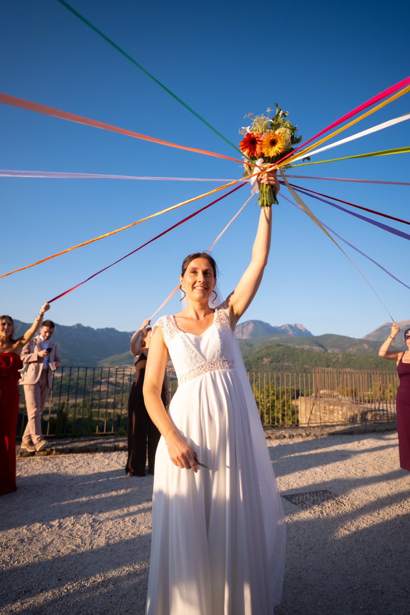 Pauline lève le bouquet attaché à des rubans de couleur