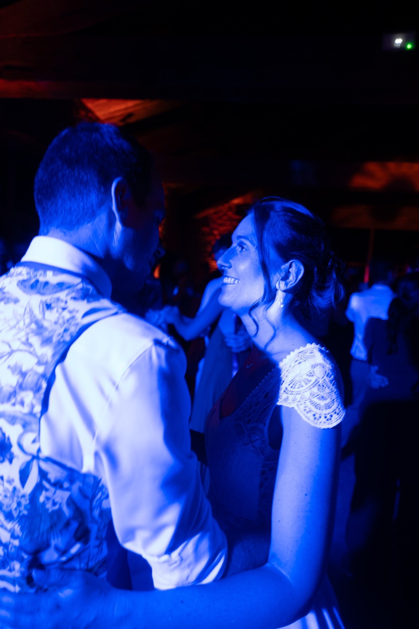 Les mariés dansent serrés sous une lumière bleue