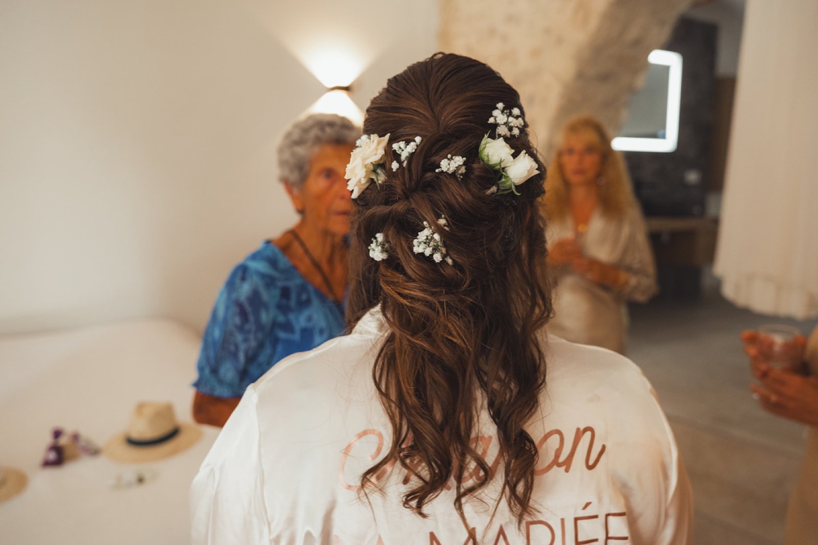 La coiffure de Manon piquée de petites fleurs blanches, vue de dos