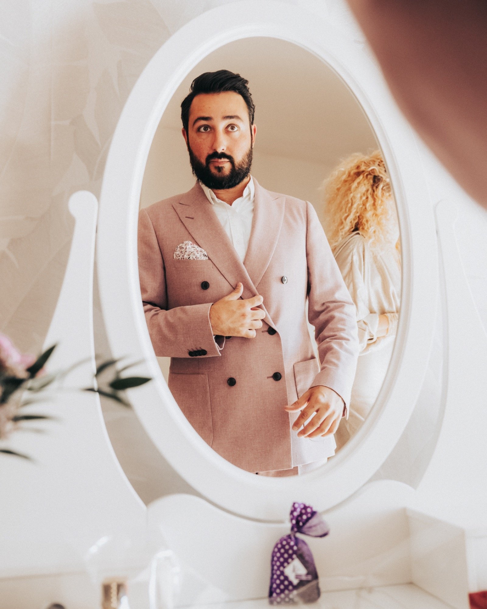 Un proche en costume rose, reflété dans un miroir ovale