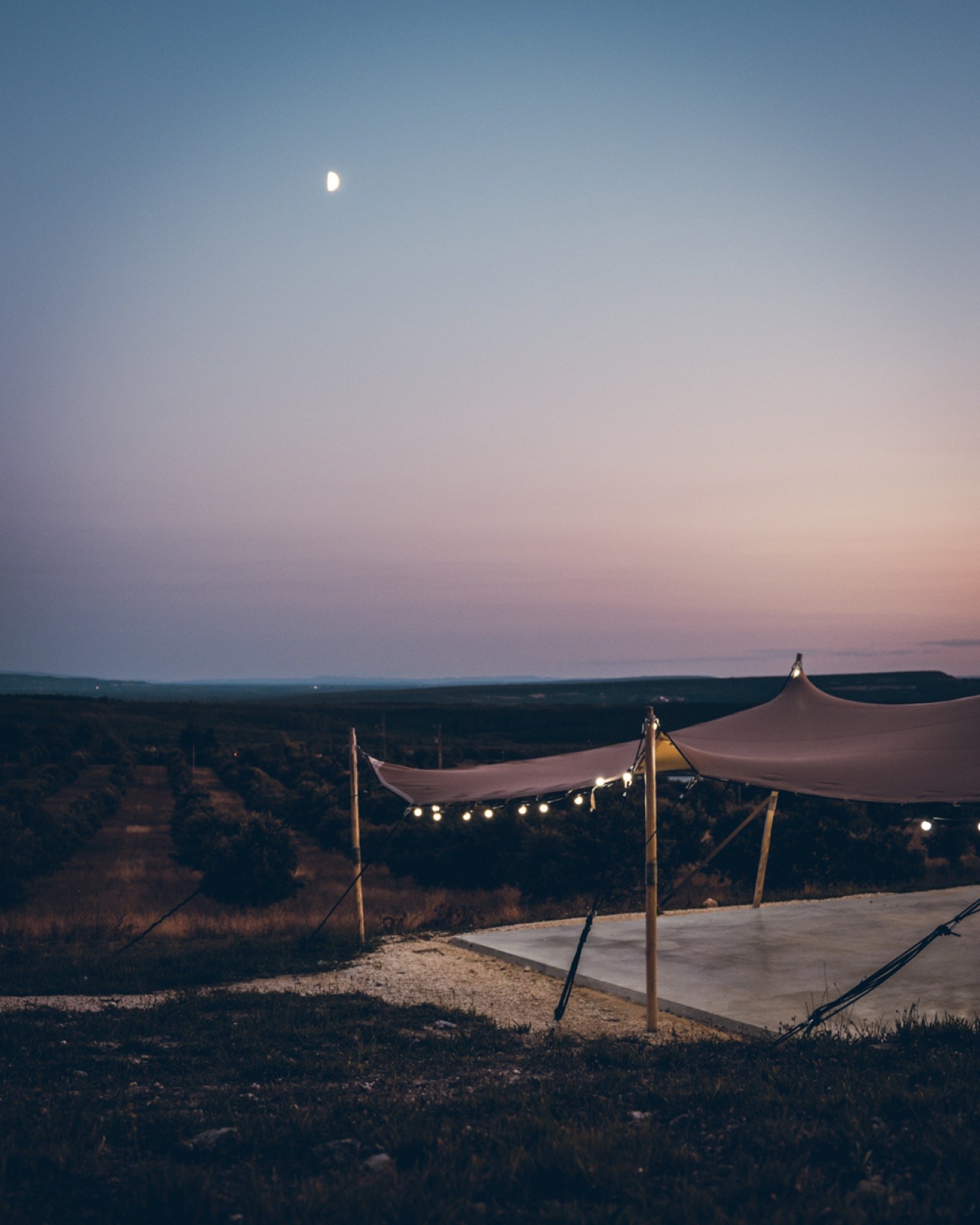 Le crépuscule, la lune et une tente tendue de guirlandes
