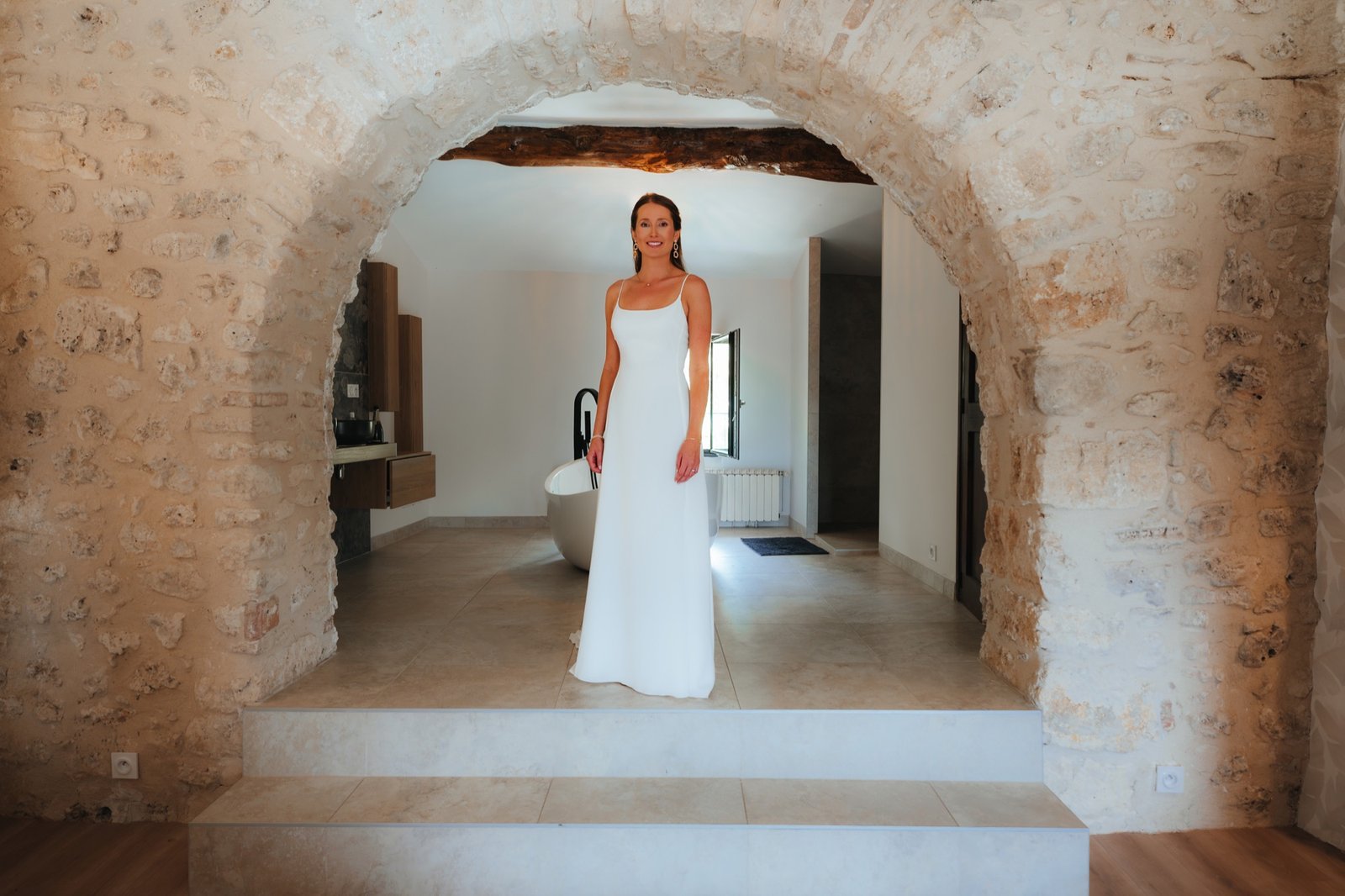 Mathilde en robe sous une arche de pierre