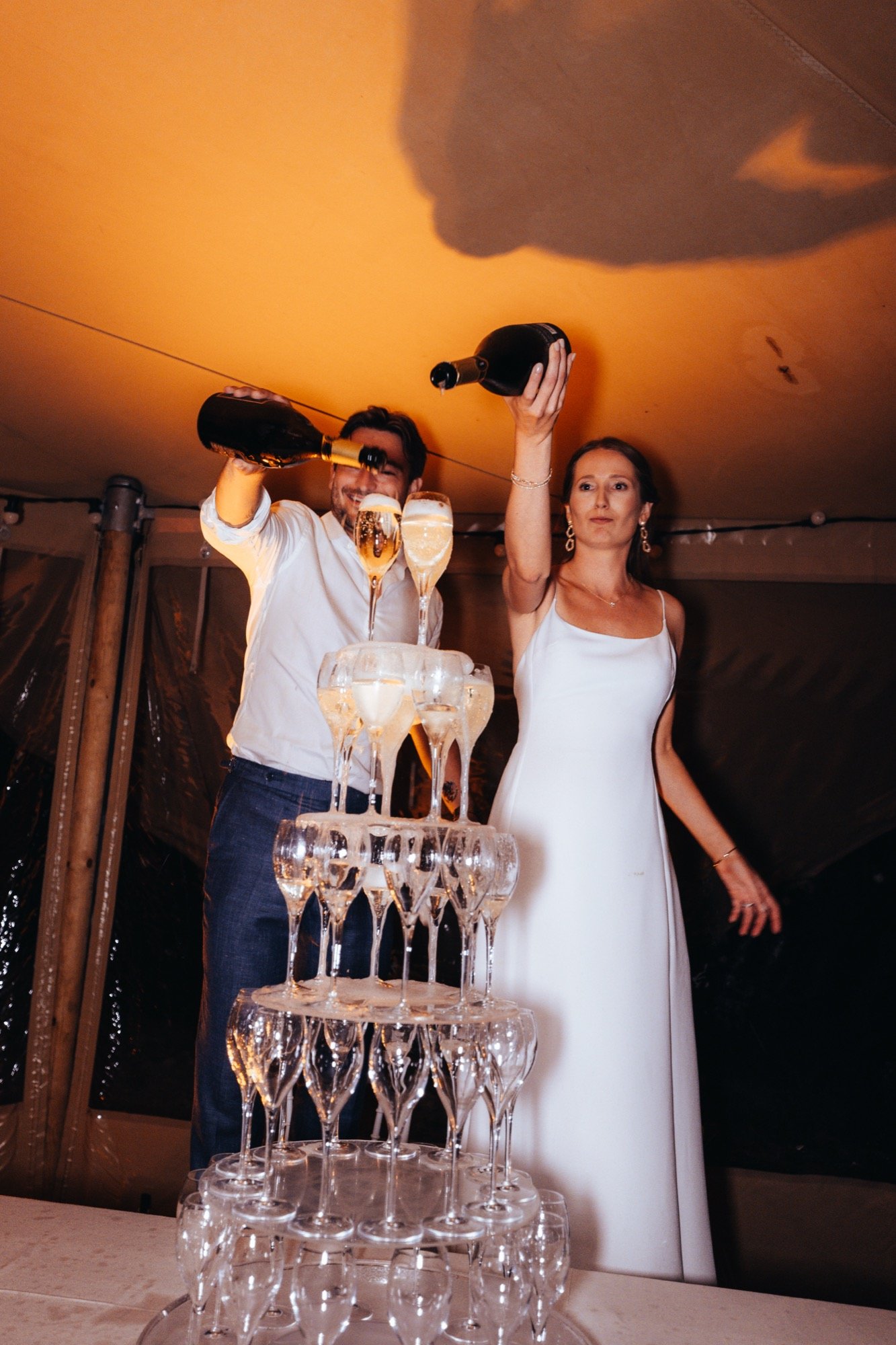Les mariés versent le champagne sur la pyramide de coupes