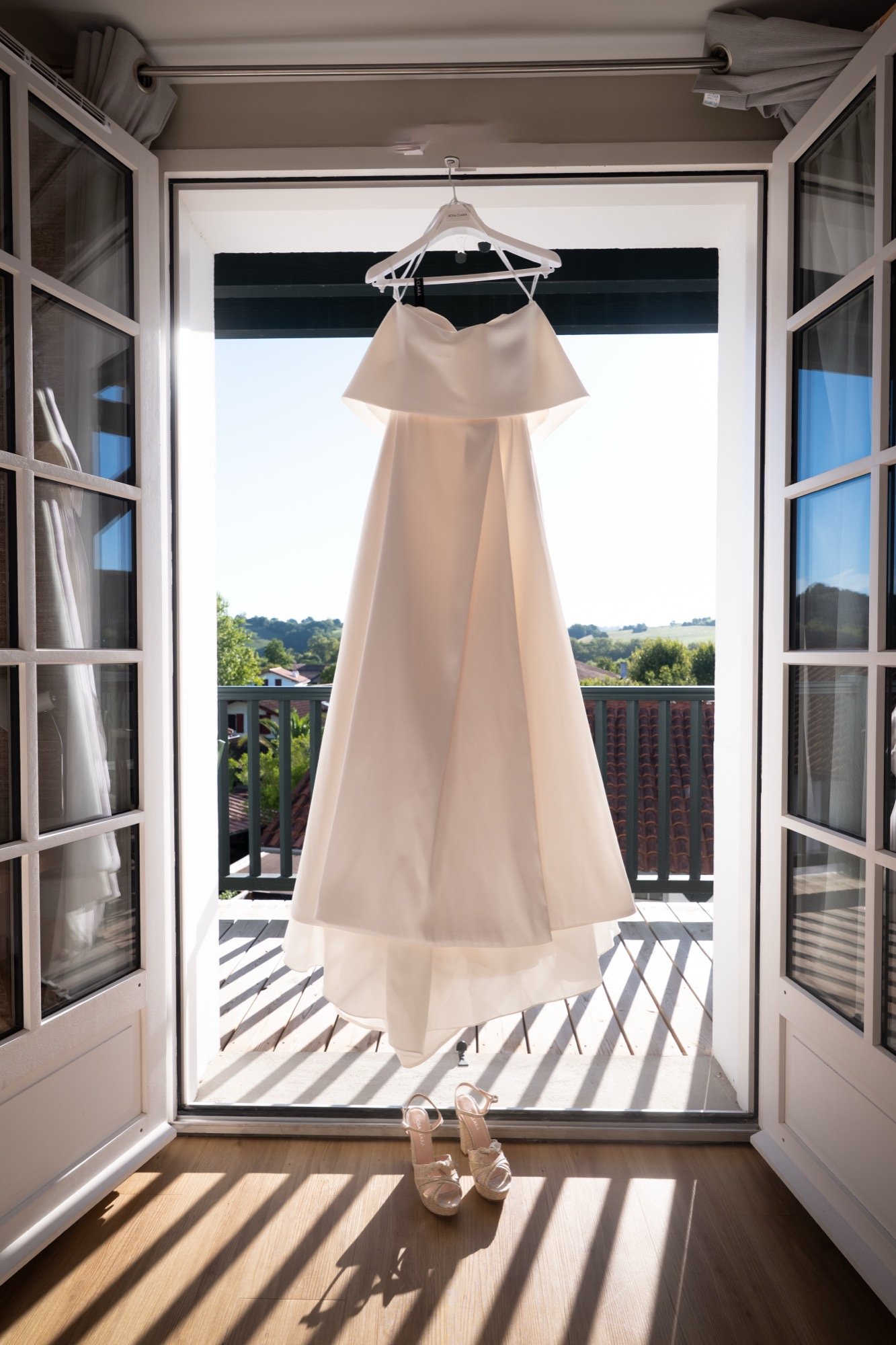 La robe suspendue dans une porte-fenêtre ouverte, ombres rayées au sol