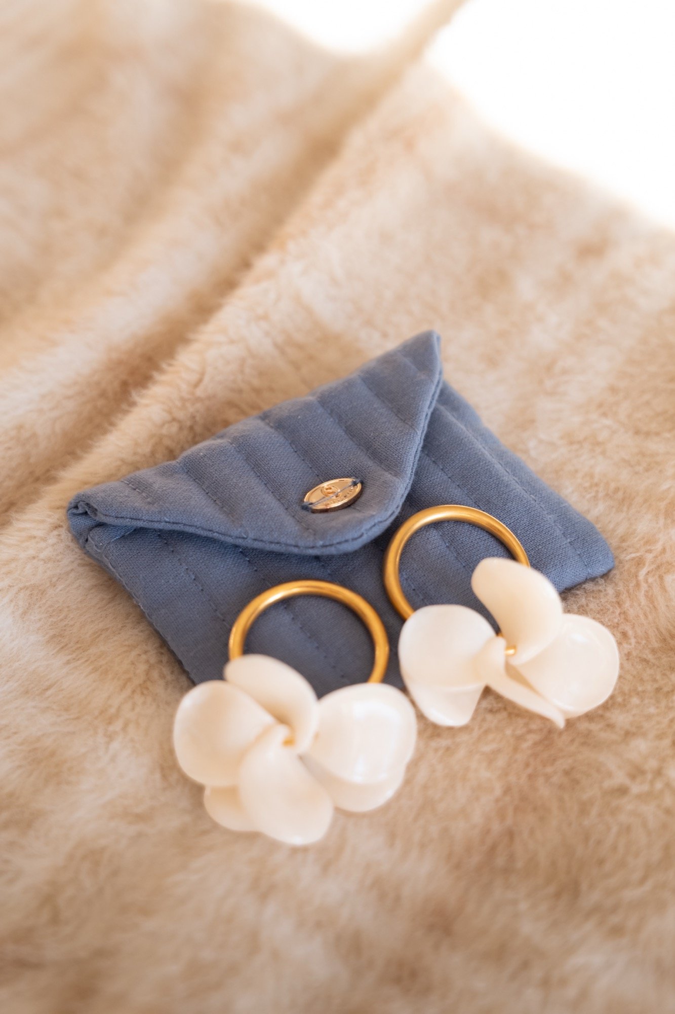 Boucles d'oreilles en fleurs et alliances sur une pochette bleue