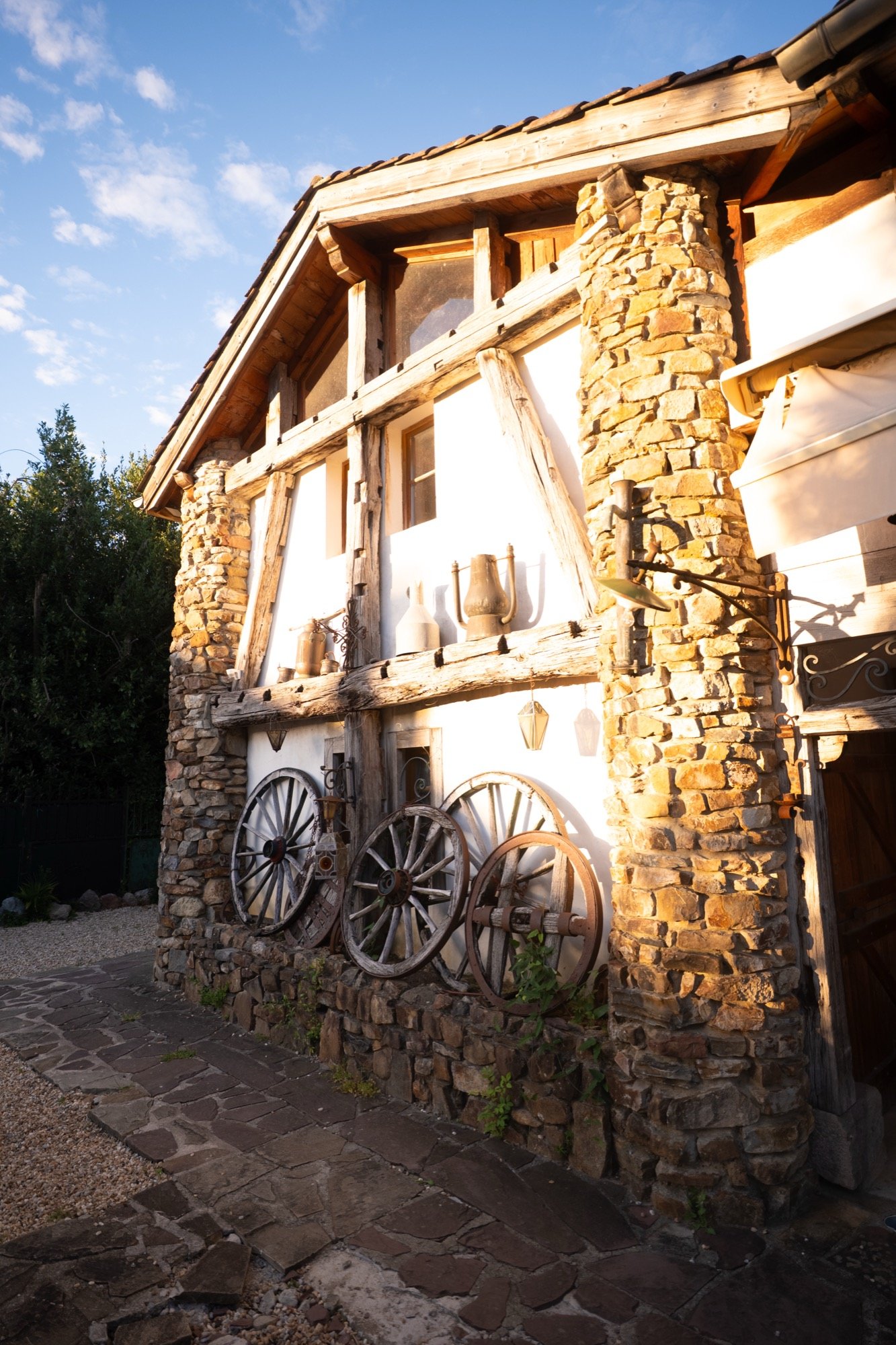 Une maison à colombages, son mur de pierre et ses roues de charrette