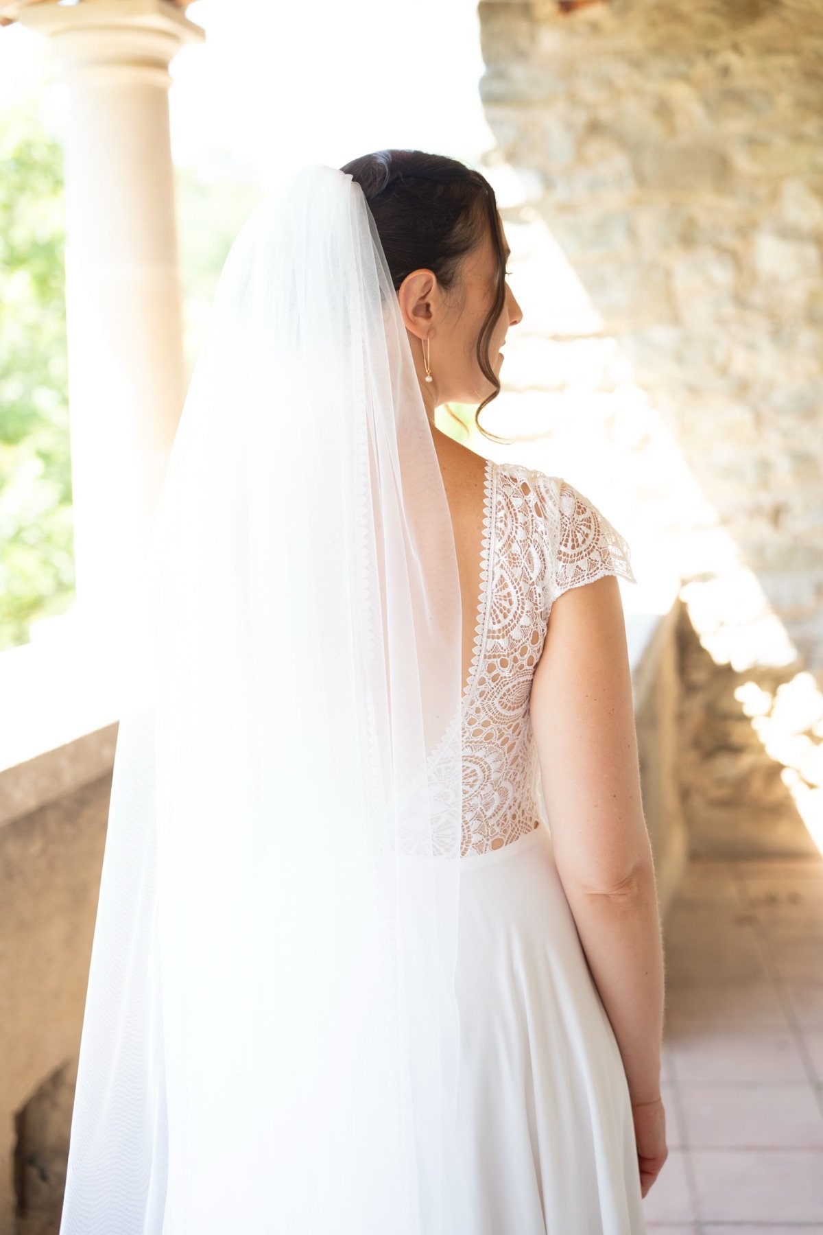 La mariée dans une loggia de pierre, son bouquet à la main
