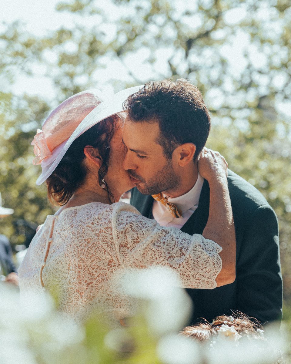 Robin enlacé par une invitée au chapeau rose, des fleurs au premier plan